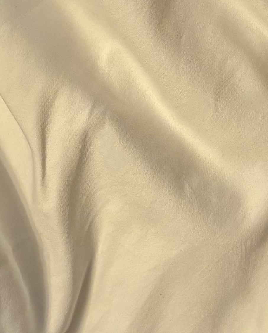 Close-up of ivory Supima cotton bedding showcasing its smooth texture, luxurious softness, and elegant drape.
